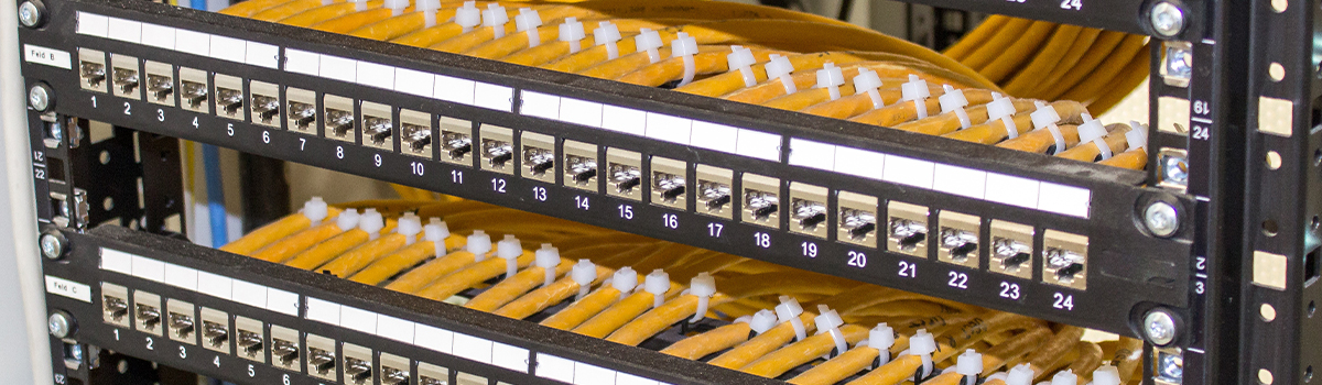Data center network cabling installation featuring organized fiber optic cables and patch panels, emphasizing high-speed connectivity and reliability for critical infrastructure.