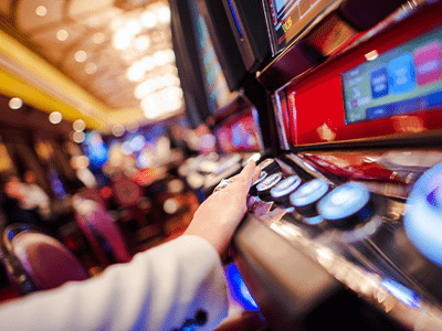 Person interacting with a slot machine in a vibrant casino setting, highlighting hospitality and entertainment industry elements relevant to network cabling services.