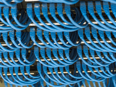 Network cabling installation with multiple blue Ethernet cables organized in a data center, illustrating Universal Fiber Optics' expertise in advanced network solutions.