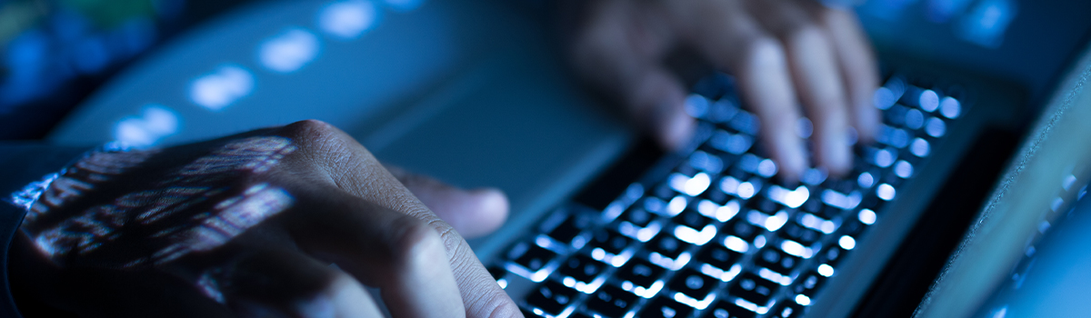 Hands typing on a laptop keyboard, illuminated by blue light, symbolizing advanced technology and data operations for data centers.