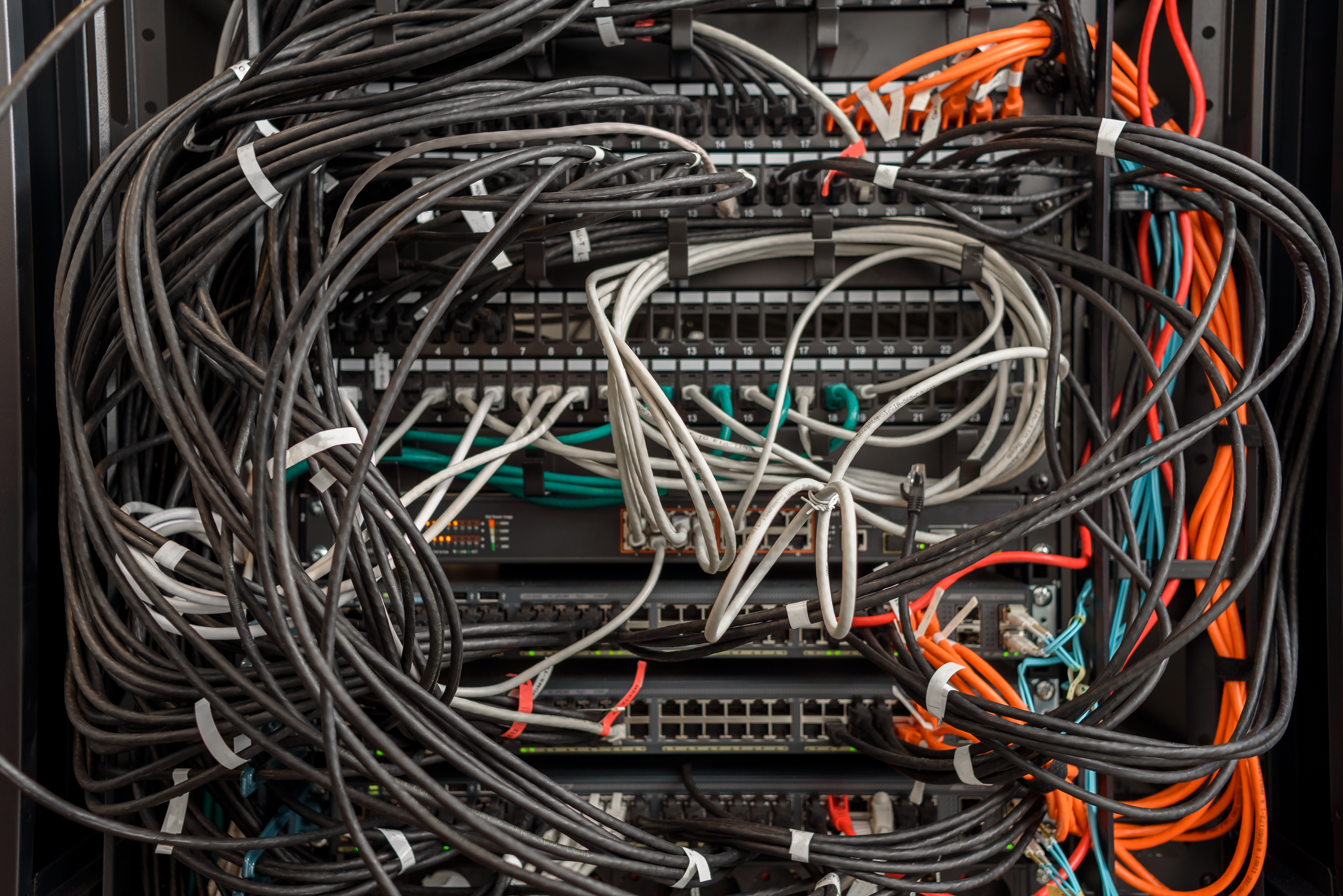Fiber optic cables and network switches in a disorganized server rack, illustrating the complexity of network infrastructure for reliable connectivity and repair services.